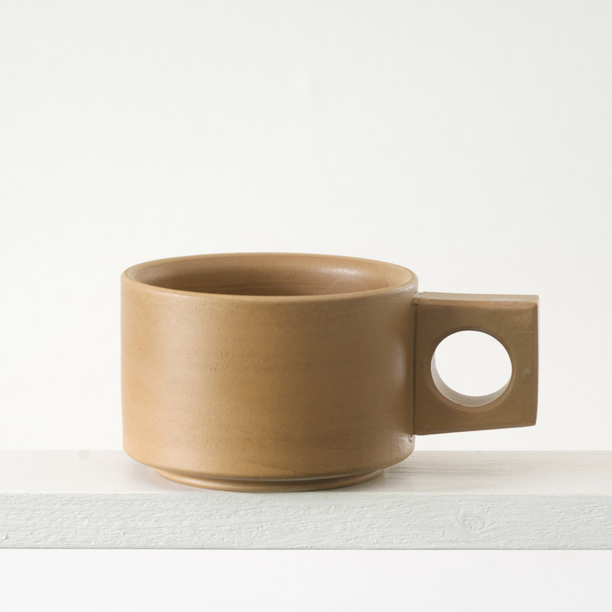 Seitenansicht einer kleinen Tasse mit einer matten, karamellfarbenen Glasur