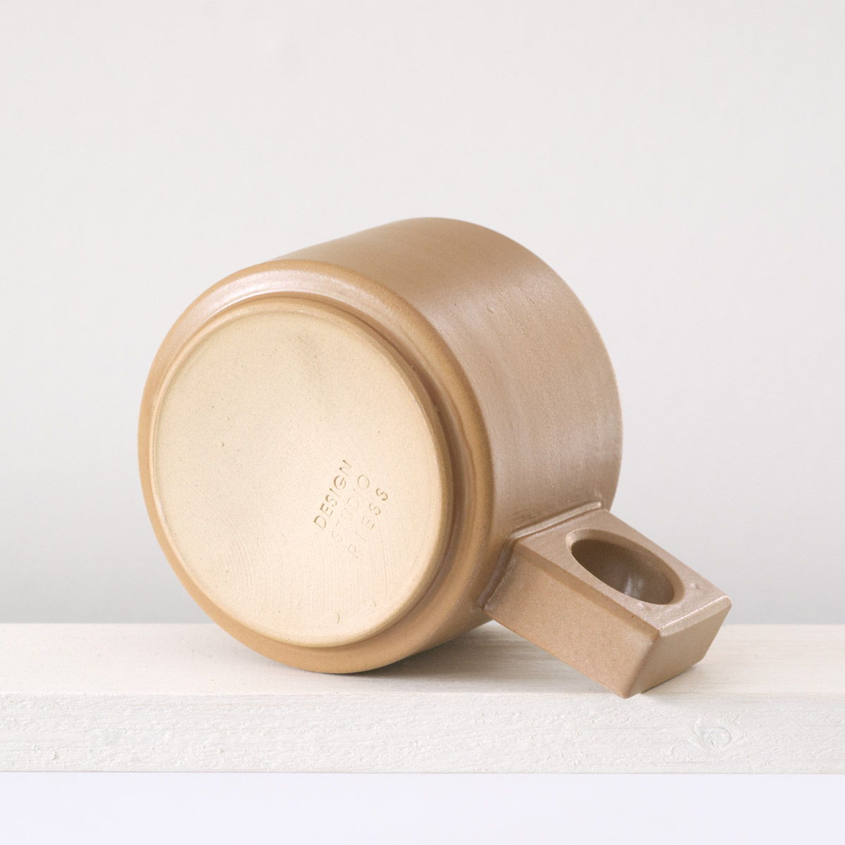 Unteransicht einer kleine Tasse mit einer matten, karamellfarbenen Glasur