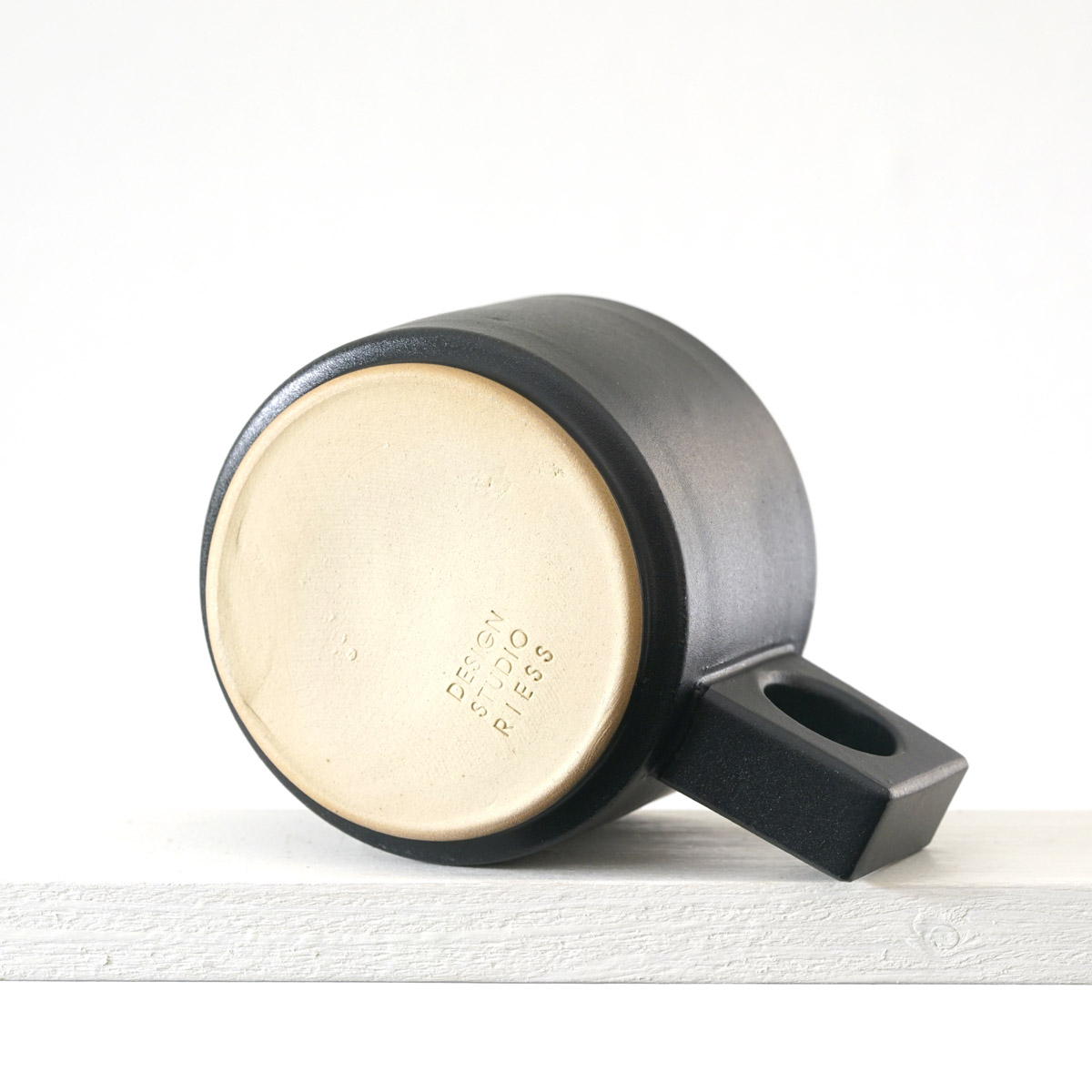 Unteransicht einer kleinen Tasse mit einer matten, schwarzen Glasur