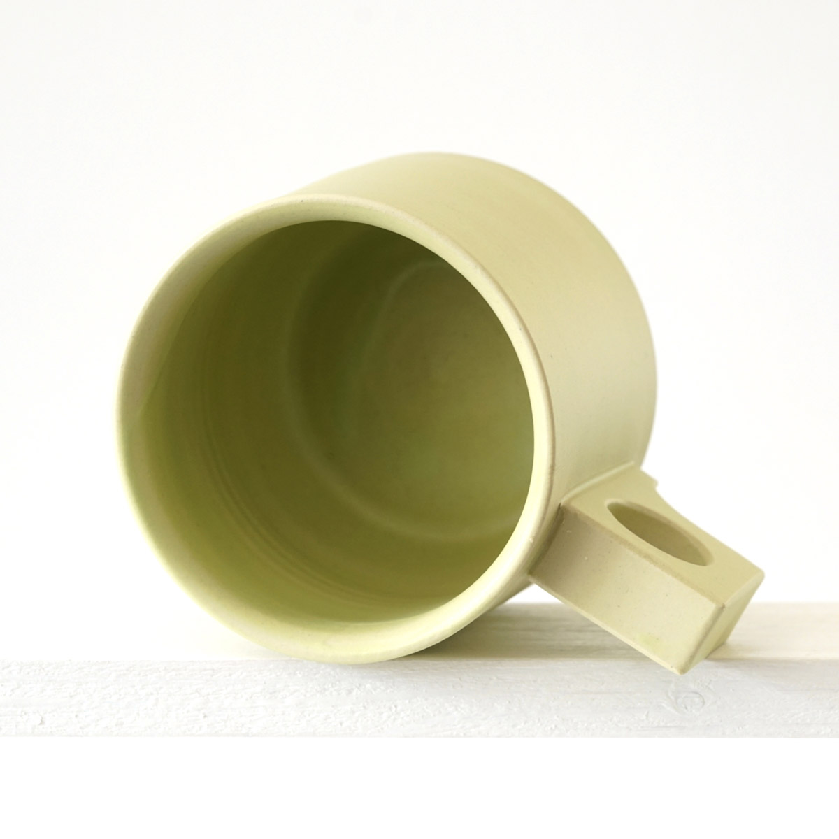 Sicht in eine große Tasse mit einer matten, limonenfarbenen Glasurn 